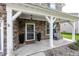 Inviting covered front porch with stone accents, decorative columns, seating, and a stylish front door at 755 Canberra Blvd, Westfield, IN 46074