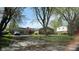 Charming one-story brick home with mature trees and a covered carport on a sunny day at 7629 Walton Dr, Indianapolis, IN 46214