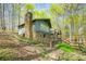 Back exterior showcasing a stone chimney, wood siding, and multiple decks in a lush, wooded setting at 8277 N Lasalle Rd, Morgantown, IN 46160
