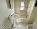 A bathroom featuring white fixtures, including a pedestal sink, tub and shower combination, and patterned flooring at 907 W 14Th St, Muncie, IN 47302