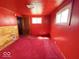 This room with red walls, carpet, and trim offers a canvas for customization and renovation to suit personal tastes at 907 W 14Th St, Muncie, IN 47302