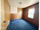 This bedroom features wood-paneled walls, blue carpet, and a window for natural light at 907 W 14Th St, Muncie, IN 47302