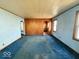 This living room offers a unique layout with light blue carpet and wood-paneled walls at 907 W 14Th St, Muncie, IN 47302