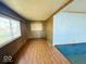 The living room features laminate flooring, wood-paneled walls, and a large window providing natural light at 907 W 14Th St, Muncie, IN 47302