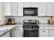 Modern kitchen with stainless steel oven and microwave, white cabinets, and neutral countertops offers style at 1114 Pennsylvania St, Columbus, IN 47201