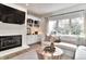 Bright living room features fireplace, custom built-ins, hardwood flooring, and a large window with natural light at 11233 Rockingham Cir, Fishers, IN 46037