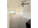 Bright living room featuring neutral walls, carpet, ceiling fan, and a front door view at 1205 N Gibson Ave, Indianapolis, IN 46219