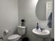 Cozy half bathroom with a round mirror, pedestal sink, and modern fixtures offers a simple, clean design at 1221 Malbec Cir, Westfield, IN 46074