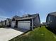 Side view of a navy blue house with a two-car garage, green grass, and blue sky at 1221 Malbec Cir, Westfield, IN 46074