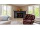 Close-up of the living room fireplace and a comfortable leather chair with windows on either side at 13 Ridgeline Dr, Brownsburg, IN 46112