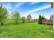 Large backyard featuring a well-maintained lawn, mature trees, and a wooden deck for relaxation and entertaining at 13728 Oliver Ln, Carmel, IN 46074