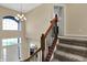 Inviting hallway featuring carpeted stairs, an elegant chandelier, and a view of the naturally lit entry at 13728 Oliver Ln, Carmel, IN 46074
