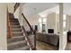 Inviting staircase featuring carpeted steps, an elegant railing, and a view of the naturally lit living area at 13728 Oliver Ln, Carmel, IN 46074