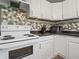 Kitchen with white cabinetry, a ceramic top range, black countertops, and tiled backsplash at 1401 E 24Th St, Muncie, IN 47302