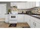 Kitchen with white cabinets, black countertops, modern appliances and geometric tiled backsplash at 1401 E 24Th St, Muncie, IN 47302