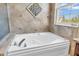 Close up of large soaking tub with tiled surround and garden window at 15329 Smithfield Dr, Westfield, IN 46074