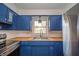 A well-lit kitchen features blue cabinets, butcher block counters, and stainless steel appliances at 1823 E 44Th St, Anderson, IN 46013