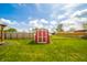View of a red and white storage shed with gable roof in a well-maintained backyard with a wood fence at 1823 E 44Th St, Anderson, IN 46013