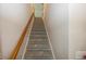 Carpeted stairway with a light wood handrail featuring neutral grey walls and white trim at 1920 E 81St St, Indianapolis, IN 46240