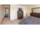 Bedroom with wooden dresser set, gray linens, and an open door to another room at 2260 Quarter Path Rd, Cicero, IN 46034