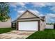 Exterior view of the home featuring a two-car garage, brick accents, and a well-maintained lawn at 2260 Quarter Path Rd, Cicero, IN 46034