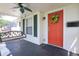 Inviting front porch with a vibrant red door, charming porch swing, and stylish ceiling fan, perfect for relaxing outdoors at 2305 Caldwell Pl, Columbus, IN 47201