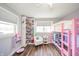 Bright bedroom featuring a pink bunk bed, white bookshelf, chair, and modern wood-look floors at 231 N East St, Pendleton, IN 46064