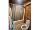 Bathroom with wooden paneling, a toilet, shower with a shower curtain, and tiled floors at 2871 N Talley Rd, Columbus, IN 47203