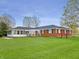 Spacious backyard showcasing a brick house, lush lawn, and an enclosed sunroom at 3710 E 750 S, Lebanon, IN 46052