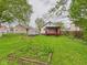 Home's backyard features a shed, a raised garden bed, and a covered red-railed porch at 411 Mccullen St, Chesterfield, IN 46017