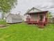 View of the backyard with green grass, small storage shed, and red-railed porch at 411 Mccullen St, Chesterfield, IN 46017
