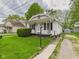 Charming home featuring white siding, a cozy front porch, and a beautifully landscaped front yard with green lawn at 411 Mccullen St, Chesterfield, IN 46017