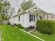 Exterior of the home showcasing the white siding, black shutters, and well-kept lawn with manicured bushes at 411 Mccullen St, Chesterfield, IN 46017