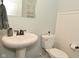 Bathroom featuring a pedestal sink, toilet, and decorative mirror against a light blue wall at 4396 Nigella Dr, Plainfield, IN 46168