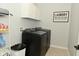 Laundry room with black washer and dryer set, white cabinets, decorative sign, and storage for laundry supplies at 4396 Nigella Dr, Plainfield, IN 46168