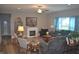 Inviting living room with a fireplace, ceiling fan, comfortable seating, and bright natural light from the large window at 4518 W Meadows Ln, New Palestine, IN 46163