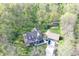 Aerial view of a modern home surrounded by lush greenery, a detached garage, and a gravel driveway at 5386 W 1100 N, Fountaintown, IN 46130