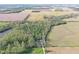 Aerial view showing a home situated by a dense forest, adjacent to open fields and a small pond at 5386 W 1100 N, Fountaintown, IN 46130
