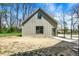 Rear exterior view showing a modern farmhouse with a black chain-link fence and yard with dirt and grass at 5386 W 1100 N, Fountaintown, IN 46130