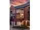 Brick townhome featuring well-maintained landscaping and private garage against a colorful sunset sky at 548 Lockerbie N Cir, Indianapolis, IN 46202