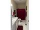 Bathroom with white vanity, tile floor, and red accents including shower curtain and towels at 5601 Harness Dr, Greenwood, IN 46143