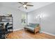 This bedroom features a futon, shelves, desk, office chair, wood floors, window and ceiling fan at 6333 Pinebark Pl, Indianapolis, IN 46217