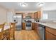 Well-lit kitchen features stainless steel appliances, wood cabinetry, and a dining area with a wooden table at 6333 Pinebark Pl, Indianapolis, IN 46217