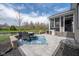 Beautiful stone patio with seating, grill, and screened-in porch overlooking the pond at 6784 W May Apple Dr, McCordsville, IN 46055