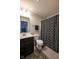 Well-lit bathroom features a dark vanity, tile floors, and a shower with a patterned curtain at 6784 W May Apple Dr, McCordsville, IN 46055