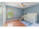Charming Bedroom featuring hardwood floors, a white crib, and a window with a pleasant view at 10220 N Serenity Ln, Mooresville, IN 46158