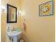 Charming powder room with a pedestal sink, decorative mirror, and warm paint at 10220 N Serenity Ln, Mooresville, IN 46158