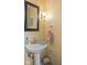 Cozy powder room featuring a pedestal sink, decorative mirror, and warm yellow walls at 10220 N Serenity Ln, Mooresville, IN 46158
