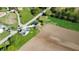 Aerial view of a quaint green home with charming porch, detached garage, and bridge access to neighborhood and farmland at 10776 S 250 W, Flat Rock, IN 47234