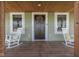 Welcoming front porch featuring rocking chairs, a dark wood door with wreath, and a 'welcome' mat at 10776 S 250 W, Flat Rock, IN 47234